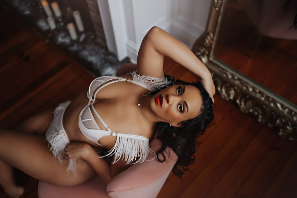 Book a boudoir session for yourself to boost confidence, with Black Lace Boudoir model posing on a couch in their luxury boudoir studio in Virginia.