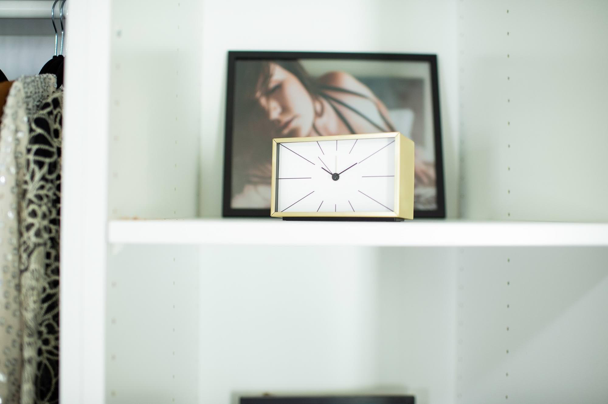 Clock and boudoir photo sitting on shelf.