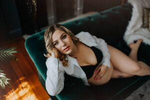best maternity boudoir near me, Virginia, Washington D.C. and Maryland featuring Black Lace Boudoir client sitting on green couch with hands on stomach.