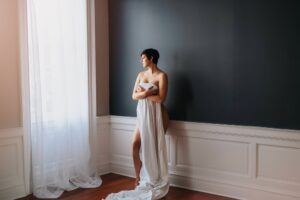 Maternity boudoir Fredericksburg, VA, at Black Lace Boudoir's professional boudoir studio with client holding white sheet.
