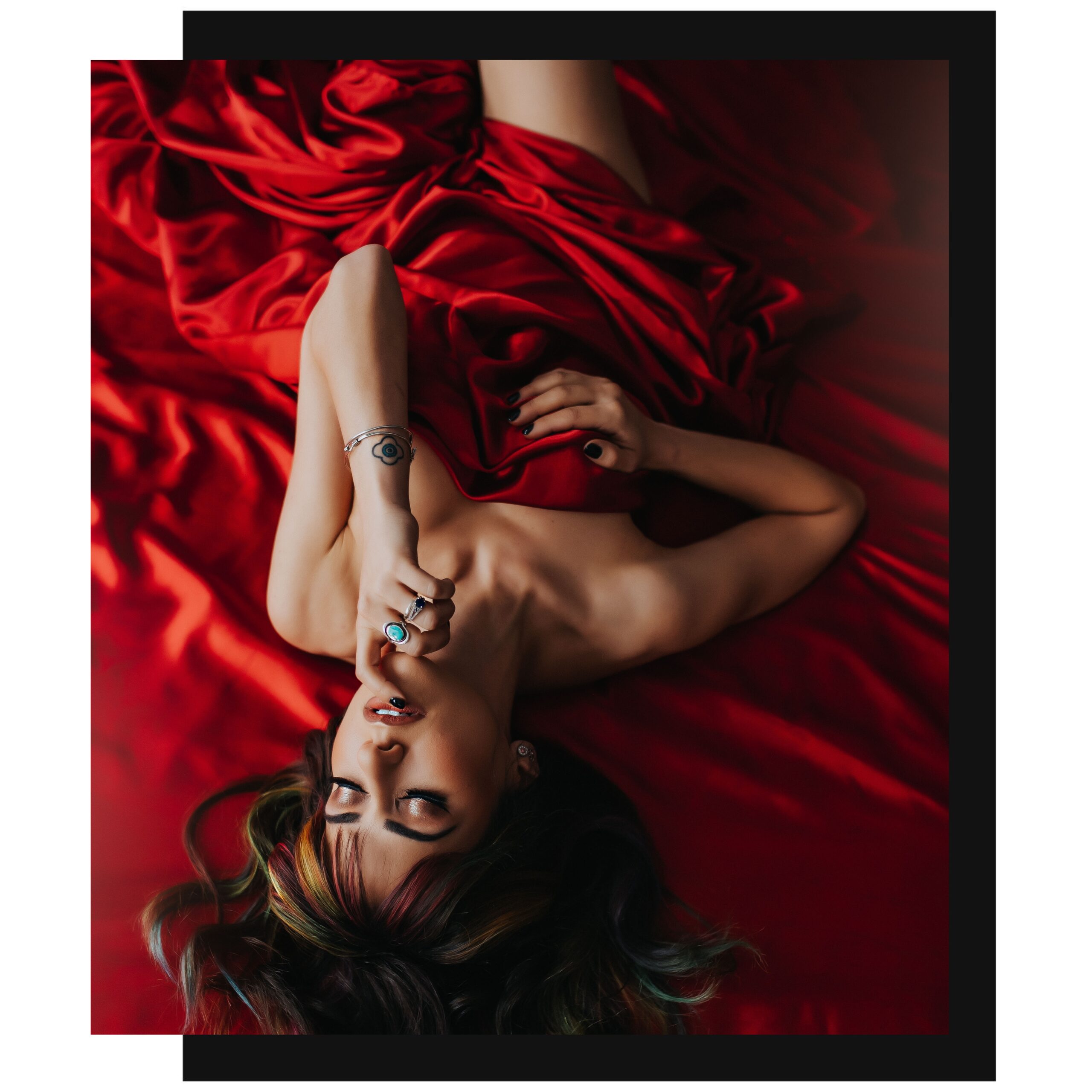 Boudoir pricing and packages for Black Lace Boudoir with picture featuring woman with red sheets.