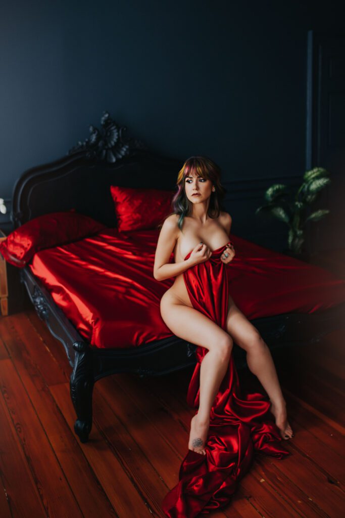 Our Boudie Babe, Ms. N, is draped in luxurious, red silky sheets during her Boudoir Model Call Session