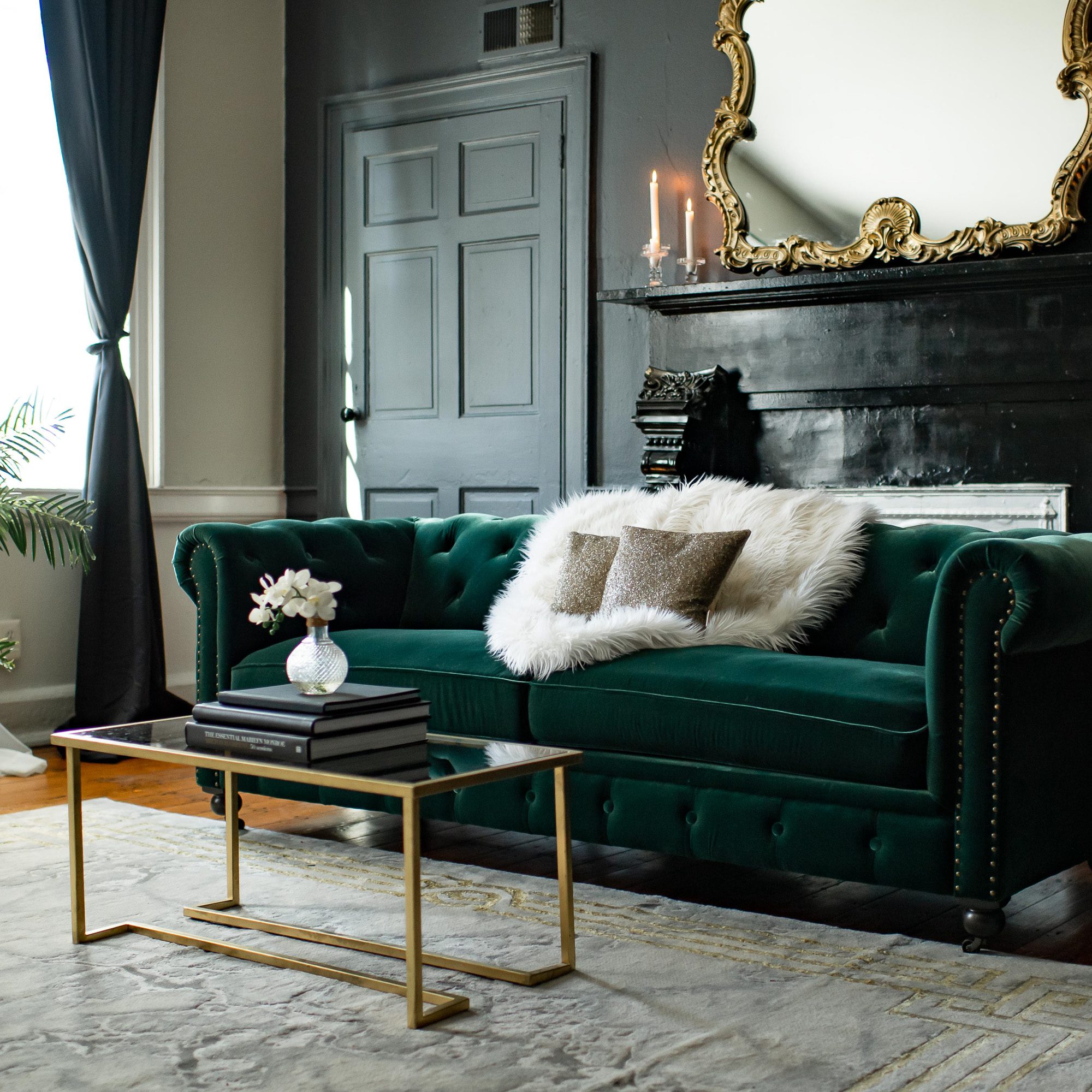 a luxury boudoir studio with a beautiful green couch, gold accents and moody lighting